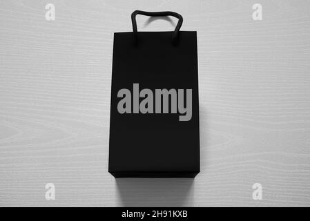 Luxuriöse, mattschwarze Einkaufstasche gegen weißes Holz von oben Stockfoto