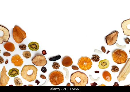 Oben sehen Zusammensetzung von getrockneten Früchten Äpfel, Orange, Kakimmon, Kiwi, Aprikosen und Nüsse auf weißem Hintergrund. Konzept der richtigen Ernährung mit leckeren getrockneten Früchten und Nüssen. Stockfoto