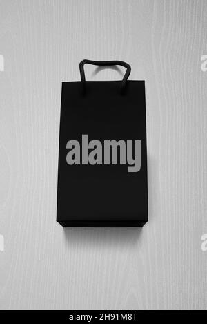 Luxuriöse, mattschwarze Einkaufstasche gegen weißes Holz von oben Stockfoto