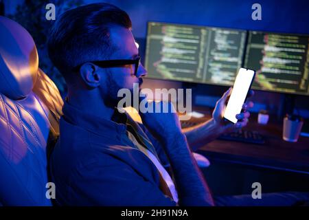 Profilfoto des gekümmerten klugen Kerls, der Hand am Kinn hat, Telefongespräch, während man das Business Center am späten Abend betrachtet Stockfoto