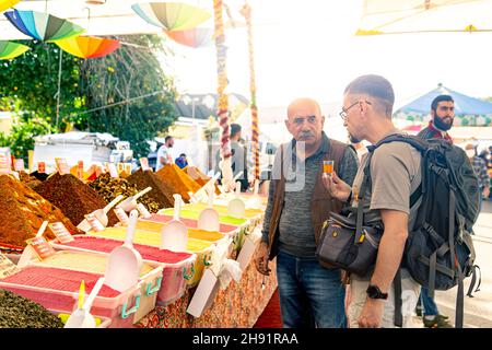 Kemer, Türkei - 08. November 2021: der basar-Händler lädt einen Touristen ein, Ingwertee zu probieren Stockfoto