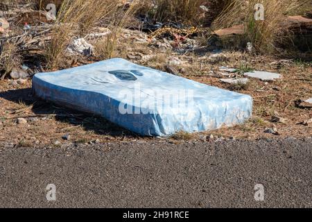 Die Matratze liegt auf der Straßenseite - eine wilde Müllhalde Stockfoto