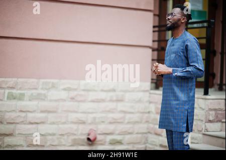 Afrikanischer Kerl in blauem authentischem Kostüm, Brille. Modischer nigerischer Mann. Stockfoto