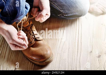 Tischler in Blue Jeans Schnürsenkel binden von gelben Schuhe auf Holzboden. Für text Stockfoto