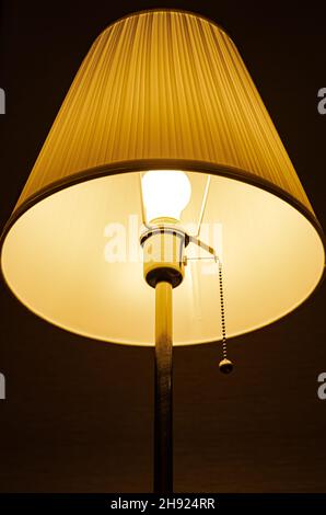 Beleuchtete Lampe, die im Dunkeln auf dem Hintergrund der Wand steht. Hochwertige Fotos Stockfoto