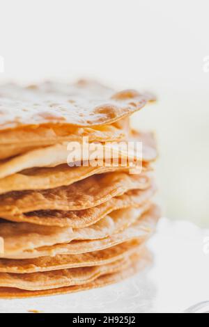 Gebackene Krümel Kuchen aus Blätterteig für Schichtkuchen auf einem Glasständer. Halbzeug für Kuchen. Nahaufnahme, selektiver Fokus, geringe Tiefe von Stockfoto