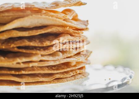 Gebackene Krümel Kuchen aus Blätterteig für Schichtkuchen auf einem Glasständer. Halbzeug für Kuchen. Nahaufnahme, selektiver Fokus, geringe Tiefe von Stockfoto