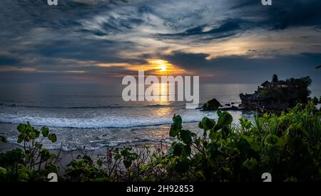 Wolkiger Himmel über dem Tana Lot Tempel und dem Meer in Bali, Indonesien bei Sonnenuntergang Stockfoto