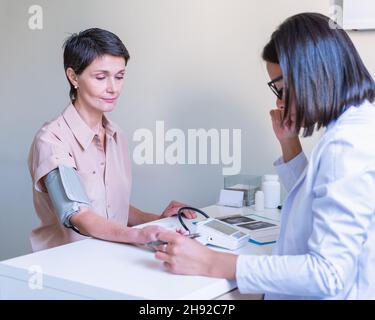 Arzt, der den Blutdruck des Patienten mit dem Sphygmomanometer in der Klinik misst Stockfoto