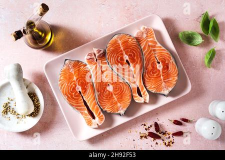 Frische Lachsscheiben auf einem rosafarbenen Teller auf einem rosafarbenen Tisch, fertig zum Kochen Stockfoto