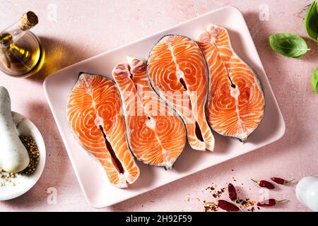 Frische Lachsscheiben auf einem rosafarbenen Teller auf einem rosafarbenen Tisch, fertig zum Kochen Stockfoto