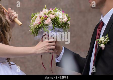 Der Bräutigam schenkt der Braut einen schönen Hochzeitsstrauß aus rosa Rosen aus der Nähe Stockfoto