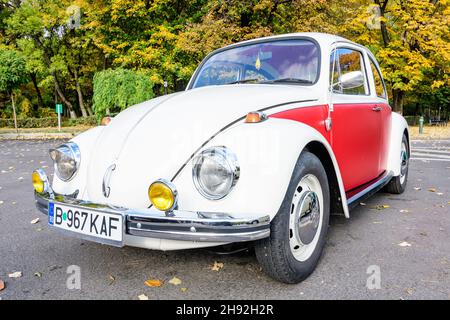 Bukarest, Rumänien, 24. Oktober 2021: Ein lebendiger rot-weißer Volkswagen Beetle deutscher Oldtimer im Verkehr auf einer Straße bei einer Veranstaltung für Oldtimer Stockfoto