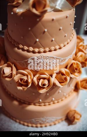 Eine schöne braune dreistufige Hochzeitstorte mit Rosen. Lecker aussehender Festkuchen. Hochwertige Fotos Stockfoto