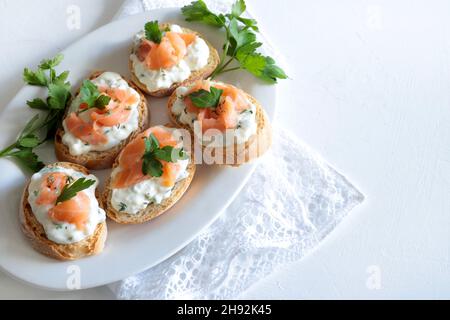 Canapés mit geräuchertem Lachs und Frischkäse auf weißem Hintergrund. Leckere Vorspeise. Direkt darüber. Stockfoto