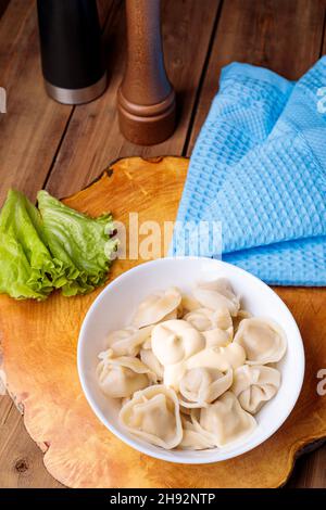 Knödel auf einem weißen Teller mit Salat auf einem hölzernen Hintergrund. Russische nationale Küche. Stockfoto