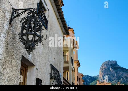 Fassade mit schöner geschmiedeter Laterne aus Metall in Polop, Alicante, Spanien. Ponoig Berg im Hintergrund. Stockfoto