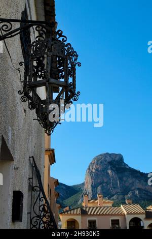 Fassade mit schöner geschmiedeter Laterne aus Metall in Polop, Alicante, Spanien. Ponoig Berg im Hintergrund. Stockfoto