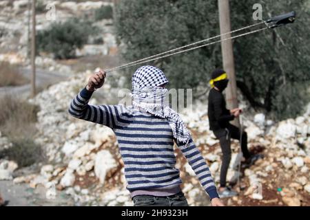 Qalqilya, Palästina. 03rd Dez 2021. Ein Palästinenser sah, wie er bei Zusammenstößen mit der israelischen Armee Steine mit einem Schleuderschuss warf. Seit 2011 protestieren Palästinenser jeden Freitag und Samstag im Dorf Kafr Kadum gegen die Schließung einer ihrer Straßen und die Beschlagnahme ihres Landes durch die israelischen Behörden. Diese Entscheidungen wurden getroffen, um die israelische Siedlung Kedumim zu erweitern. (Foto von Nasser Ishtayeh/SOPA Images/Sipa USA) Quelle: SIPA USA/Alamy Live News Stockfoto