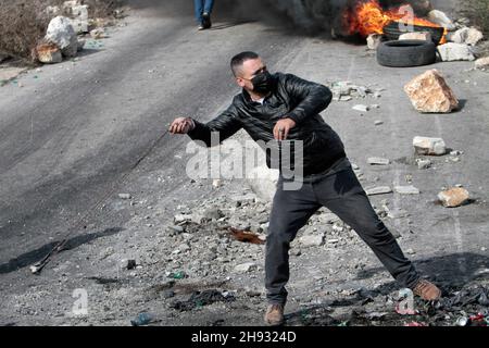 Qalqilya, Palästina. 03rd Dez 2021. Ein Palästinenser sah, wie er bei Zusammenstößen mit der israelischen Armee Steine mit einem Schleuderschuss warf. Seit 2011 protestieren Palästinenser jeden Freitag und Samstag im Dorf Kafr Kadum gegen die Schließung einer ihrer Straßen und die Beschlagnahme ihres Landes durch die israelischen Behörden. Diese Entscheidungen wurden getroffen, um die israelische Siedlung Kedumim zu erweitern. (Foto von Nasser Ishtayeh/SOPA Images/Sipa USA) Quelle: SIPA USA/Alamy Live News Stockfoto