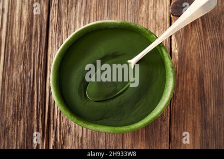 Grünes Chlorella-Algenpulver in einer Schüssel auf einem Tisch, Draufsicht Stockfoto