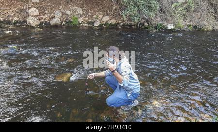 Jugendlicher nimmt Wasserprobe, um Wassereigenschaften zu analysieren Stockfoto