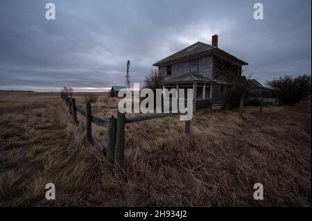 Verlassene und zerbrochene alte Farmen und Gehöfte mit dunklem und unheilvollen Himmel in Alberta, Kanada Stockfoto