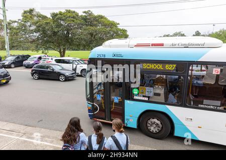 Australische Jahr 12 Mädchen Studenten an der Schulbushaltestelle, als Schulbus ankommt, Sydney, NSW, Australien Stockfoto