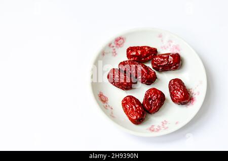 Getrockneter chinesischer roter Jujube in einem Teller, isoliert auf weißem Hintergrund. Stockfoto