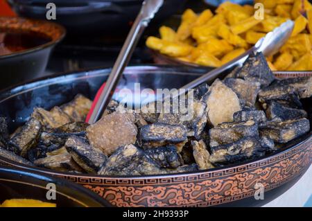 Schwarzer chinesischer Stinky Tofu in großer Platte vom China Local Street Market aus gesehen. Tief gebratene (gelb) Stinky Tofu verschwommen auf dem Hintergrund. Stockfoto