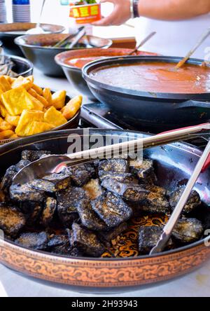 Schwarzer chinesischer Stinky Tofu in großer Platte vom China Local Street Market aus gesehen. Rote Chilisauce verschwommen auf dem Hintergrund. Stockfoto