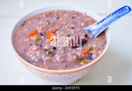 Gesunde chinesische hausgemachte Multi-Grain-Brei in einer Schüssel mit Jujube und Goji-Beere auf der Oberseite und isoliert auf hellem Hintergrund. Stockfoto