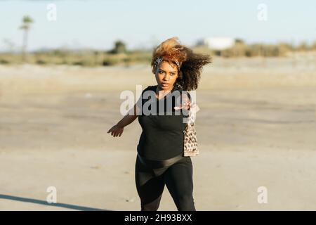 Eine Schwangerin, die Yoga praktiziert, steht am Strand Stockfoto