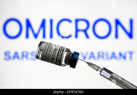 COVID-19-Impfstoff und Spritze auf dem Hintergrund der Omicron-Varianteninfo, Schwerpunkt auf der Impfstoffflasche mit Coronavirus. Konzept der neuen Corona-Virusstämme, Impfstoff Stockfoto