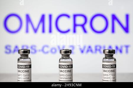 Omicron COVID-19-Variante und Corona-Virus-Impfstoff, Schwerpunkt auf Impfstoffflaschen. Konzept der Gefahr, neue Coronavirus-Stämme, Impfstoffforschung, Wiedereröffnung, Stockfoto