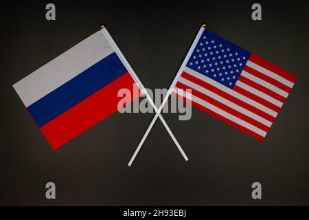 Die russische Flagge und die US-Flagge kreuzen sich auf schwarzem Hintergrund. Russland gegen USA. Treffen zwischen den Präsidenten Russlands und der Vereinigten Staaten Stockfoto