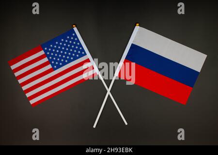 Die USA-Flagge und die russische Flagge kreuzen sich auf schwarzem Hintergrund. USA gegen Russland. Treffen zwischen den Präsidenten der Vereinigten Staaten und Russi Stockfoto