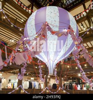 Ansicht von oben nach unten einer riesigen hängenden Heißluftballondekoration im Liberty Store in der Regent Street für Weihnachtseinkäufer, London England, Großbritannien Stockfoto
