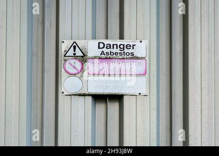 Asbest-Gefahrenschild an der alten verzinkten Schschuppen-Wand. Stockfoto