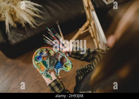 Nahaufnahme der Hände einer unbekannten Malerin, die Farbpalette und Pinsel hält, um die Freizeitgestaltung der Kunst professionell oder ama zu machen Stockfoto