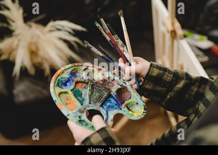 Nahaufnahme der Hände einer unbekannten Malerin, die Farbpalette und Pinsel hält, um die Freizeitgestaltung der Kunst professionell oder ama zu machen Stockfoto