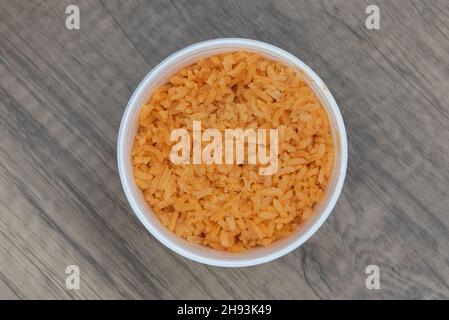 Ansicht von oben über eine großzügige Portion mexikanischen Reis in einem kleinen Behälter, der als Beilage zum Essen gegessen werden kann. Stockfoto