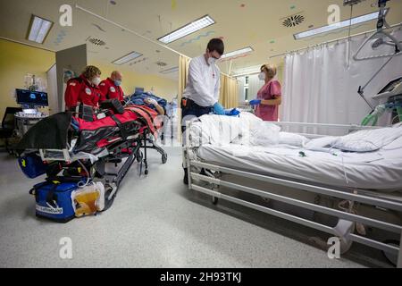 02. Dezember 2021, Baden-Württemberg, Öhringen: Die Rettungsärztin Eva Müller (l.) und der Notarzt Georg Berg (2nd v.l.) verlegen einen Patienten während einer Mission aus einem Bett auf der Intensivstation des Hohenlohe Krankenhauses, um ihn zum DRF-Rettungshubschrauber Christoph 51 zu bringen, der in der Nähe des Krankenhauses gelandet war. Während der Mission transportierte der DRF einen Patienten ohne Covid-19 im DRF-Rettungshubschrauber Christoph 51 von der Intensivstation des Krankenhauses Hohenlohe auf die Intensivstation einer Reha-Klinik in Bayern. Covid 19 Patienten sind nicht die einzigen wh Stockfoto
