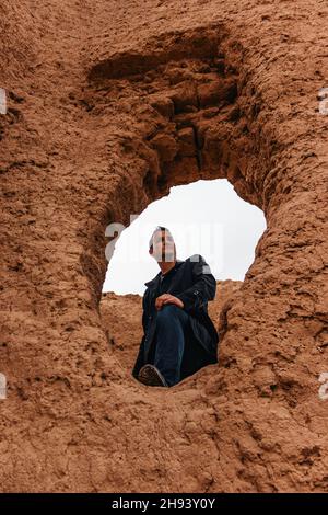 Porträt eines Mannes in dunklem Outfit, der in einer alten Sandsteinburg steht. Stockfoto