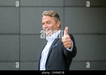 Porträt eines eleganten und erfolgreichen Geschäftsmannes, der den Daumen als ähnlich zeigt und sich mit der Genehmigung meldet, während er selbstbewusst auf die Kamera blickt Stockfoto