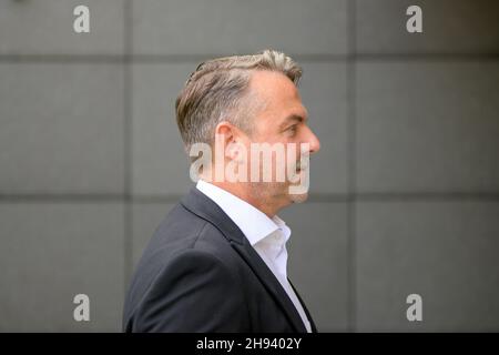 Seitenansicht Porträt eines selbstbewussten, gutaussehenden Mannes mittleren Alters, der ein elegantes weißes Hemd und eine Jacke an der grauen Wand trägt, um Platz für Kopien zu schaffen Stockfoto