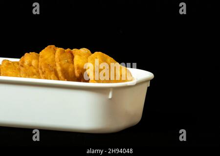 Farsi Puri in quadratischer weißer Schale, Kopierbereich auf der rechten Seite, Nahaufnahme, isoliert auf schwarzem Hintergrund, Gujarati und indische Snacks, weißes Mehl (Maida) Stockfoto