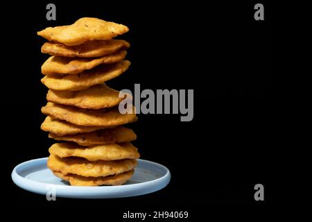 Stapel Farsi Puri, Kopierraum auf der rechten Seite, isoliert auf schwarzem Hintergrund, Gujarati und indische Snacks, Weißmehl (Maida), Namkeen, Crispy, Crunchy Stockfoto