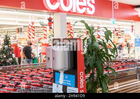 Covid 19 Pandemie, Händedesinfektionsstation für Kunden vor dem Coles Supermarkt in Sydney, Kunden mit Gesichtsmasken, omicron-Variante entdecken Stockfoto