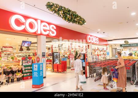 Zwei australische Frauen mit einem kleinen Kind werden am Eingang zum Coles Supermarkt in Sydney zum Weihnachtseinkäufe mit Gesichtsmasken getragen, covid 19 Global Stockfoto